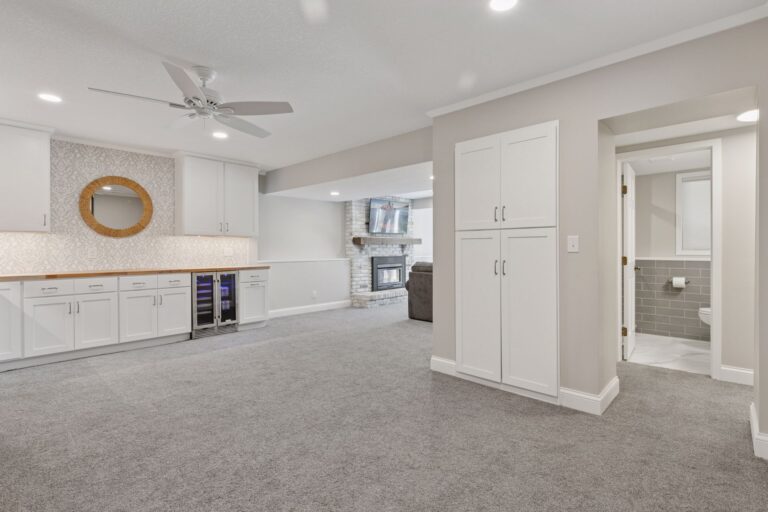 Modern basement with a wet bar, fireplace, and adjacent bathroom.
