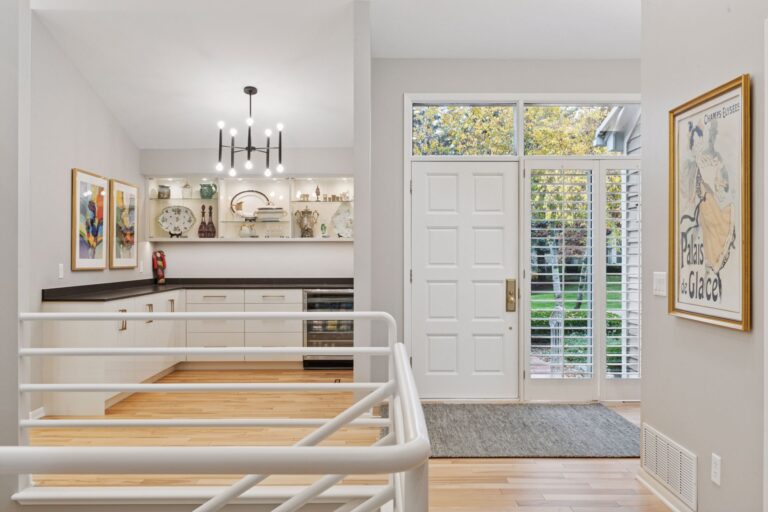 Modern bathroom with white soaking tub, light tile shower surround, built-in niche, and natural wood cabinetry in Minnetonka home remodel.
