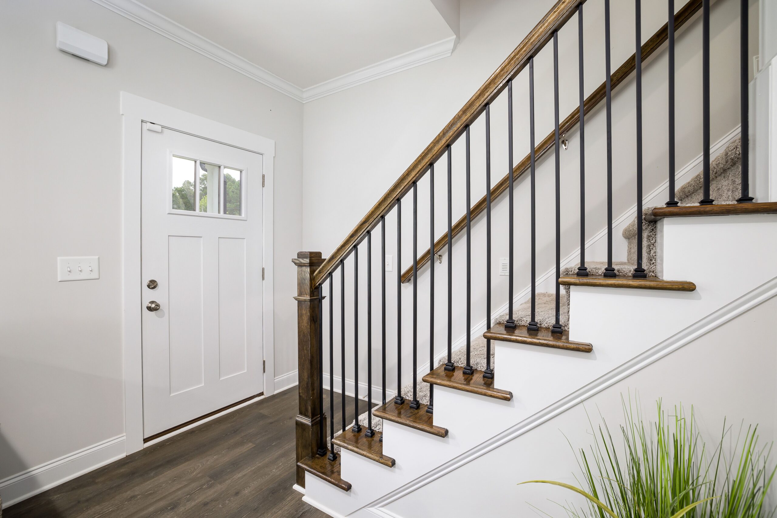 Modern interior staircase with wood treads, black metal balusters, and an entryway, highlighting key design elements for a second-story home addition.